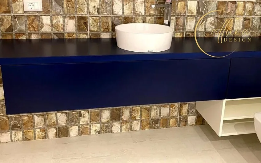 Mobilier de lavoar suspendat, bleumarin, cu lavoar rotund alb pe blat, pe un perete cu mozaic în tonuri de chihlimbar