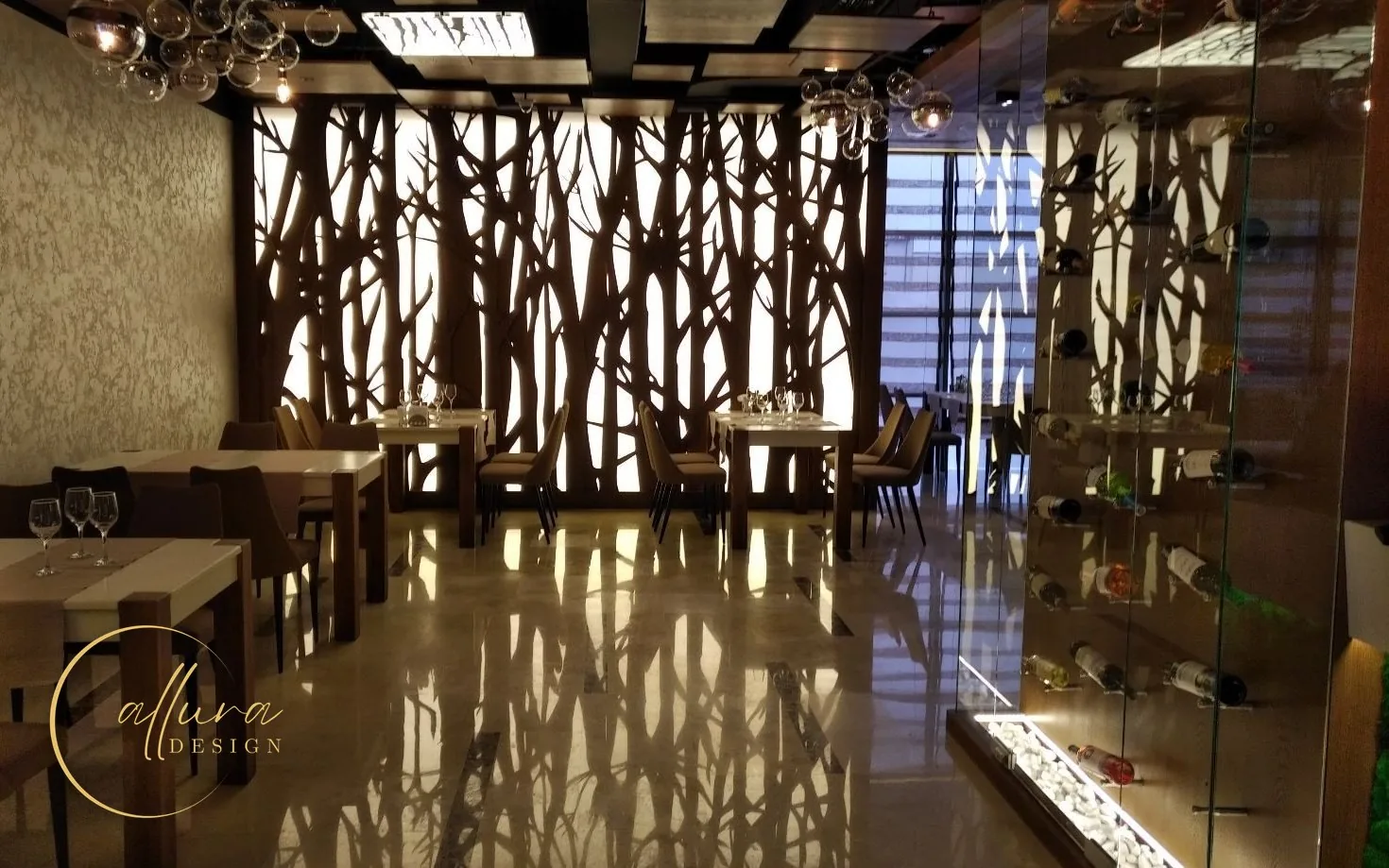 Restaurant cu un paravan retroiluminat cu siluete de copaci, pardoseală din piatră lustruită și vitrină de vinuri din sticlă